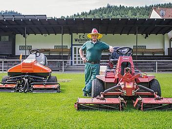 Nur echt mit Hut: Die schwarz-rot-goldene Kopfbedeckung gehört für Georg Heibl dazu, wenn er mit seinen Traktoren den Rasen auf die passende Länge bringt. Auf vier Zentimeter ist der 17 000 Euro teure linke Rasenmäher während der Saison eingestellt. Foto: Marian Hamacher