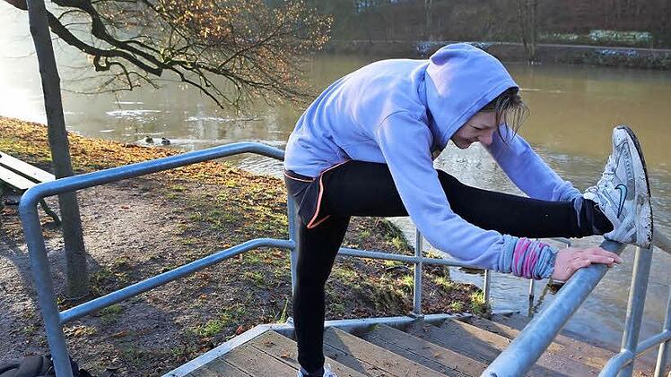 Nach Nieselregen und Schneematsch am Wochenende wird Brigitta Muntendorf in der neuen Woche vom Sonnenschein begrüßt. Nach ihrer individuellen Laufrunde macht sie noch ein paar Dehnübungen, bevor sie ohne zu Zögern in die klirrend kalte Regnitz steigt.   Fotos: Barbara Herbst
