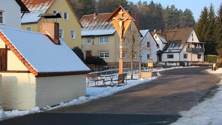 Im Zuge der Dorferneuerung in Rüssenbach wurde beim Backofen neben dem Kreuz ein Aufenthaltsbereich geschaffen und die Straße gepflastert. Dank fehlender Ausbau-Beitragssatzung mussten sich die Anlieger an den Kosten nicht beteiligen. Foto: Josef Hofbauer