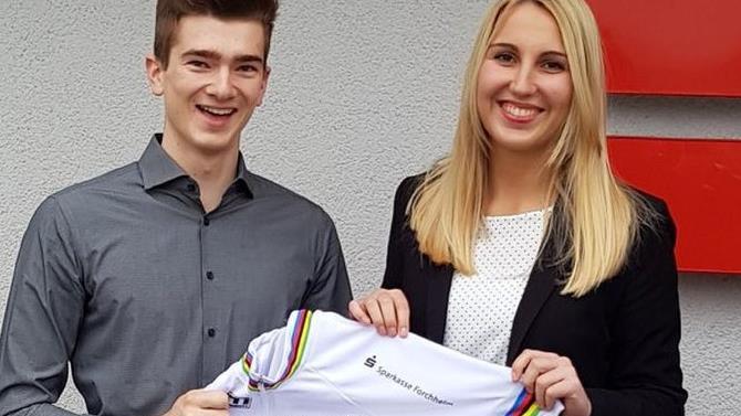 Das neue Regenbogentrikot des Weltmeisters ist da: Lukas Kohl hat das Einzelstück selbst anfertigen lassen und mit den Logos seiner Sponsoren verziert. Dieses präsentiert er derzeit seinen Unterstützern, wie der Sparkasse Forchheim um Barbara Eberlein (re.). privat