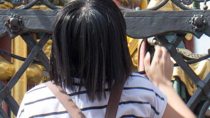 Eine junge Chinesin dreht am glücksbringenden nahtlosen Ring am Schönen Brunnen in Nürnberg. Foto: Hein
