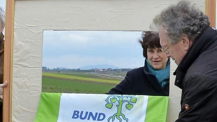 Mit einem Bilderrahmen lenken Dagmar Escher und Hubert Weiger den Blick auf das Gelände für den geplanten Flugplatz. Foto: Rainer Lutz