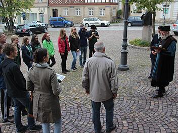 Cranach-Darsteller Wolfgang Eckert-Hetzel und Zweite Bürgermeisterin Angela Hofmann (von rechts) berichteten den Gymnasiasten am Cranach-Denkmal (im Hintergrund) auf dem Kronacher Marktplatz aus dem Leben von Lucas Cranach.  Foto: Marco Meißner