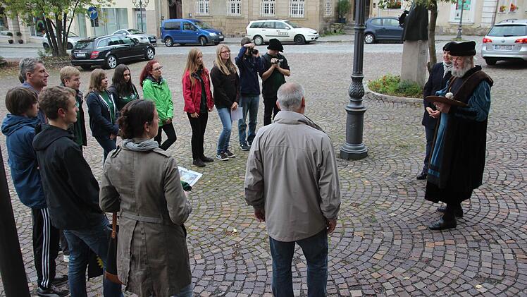Cranach-Darsteller Wolfgang Eckert-Hetzel und Zweite Bürgermeisterin Angela Hofmann (von rechts) berichteten den Gymnasiasten am Cranach-Denkmal (im Hintergrund) auf dem Kronacher Marktplatz aus dem Leben von Lucas Cranach.  Foto: Marco Meißner