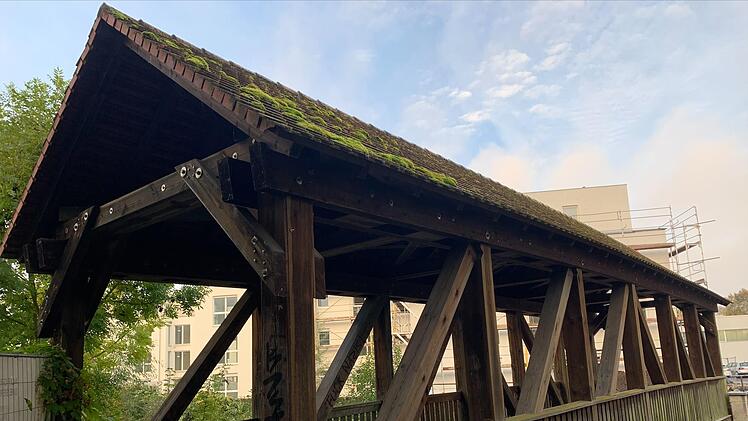 Die mit der Verschnaufpause: Die Holzbrücke, die den Vorderen Floßanger mit dem Bereich an der Stocke-Anlage verbindet, ist noch nicht sehr alt: 1988 wurde sie im Zuge der Hochwasserfreilegung  errichtet. Trotzdem hat sie bereits einiges erlebt: Besucher von Fußballspielen laufen über sie; als direkt nebenan noch ein Getränkemarkt war, erfreute sich das überdachte Bauwerk bei Gelegenheitstrinkern großer Beliebtheit. Aktuell wird ihr eine Verschnaufpause gegönnt: Wegen des Bauprojekts auf dem ...