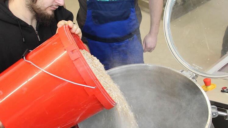 Andreas Ludwig (links) und Jonas Stöhr beginnen mit dem Einmaischen. In der Sudpfanne müssen die Kochtemperaturen - 20 Minuten bei 63 Grad, 40 Minuten bei 72 Grad und dann 78 Grad - genau eingehalten werden. Anschließend werden die Malzreste im Läuterbottich rausgefiltert.