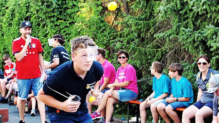 Ein Akteur der Soldatenkameradschaft fängt mit dem am Kopf befestigten Becher den ihm zugeworfenen Ball.