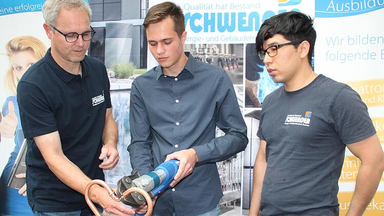 Bernd Münch von der Firma Schwender zeigt Florian El-Sayed (Mitte), wie man mit einer Fitting-Presse ein Kupferherz zusammenpresst. Lehrling Mohammed Zaki Sharifi (rechts) schaut zu. Foto: Stephan Stöckel