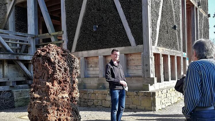 Matthias Lotz, Leiter Gebäudemanagement der Staatsbad GmbH, erklärt vor dem Gradierbau den durch Mineralienrückstände versteinerten Block aus Schwarzdorn-Reisig.