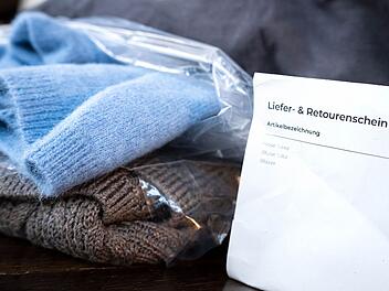 Liefer- und Retourenschein liegt neben online bestellter Kleidung