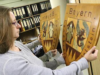 Die Staffelsteiner Museumsleiterin Adelheid Waschka zeigt eines der letzten Relikte des Landkreises Staffelstein: Dieses 1980 von Max Förster aus Unterzettlitz handgefertigte Landkreiswappen hing wohl  im Amtszimmer des Staffelsteiner Bürgermeisters Reinhard Leutner. Foto: Matthias Einwag