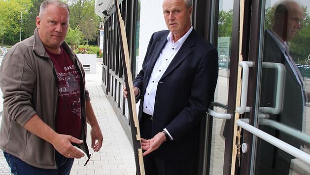 H&ouml;chstadts B&uuml;rgermeister Gerald Brehm (rechts) und Betriebsleiter Hans-Peter Philipp mit einem Teil der aufgebrochenen T&uuml;r zur W&auml;rmehalle des Freibads. Foto: Andreas Dorsch