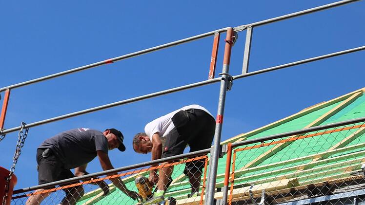 Steffen Stauch (links) und sein Kollege befestigen Leisten auf einem Dach in der Schwedenstraße. An heißen beginnt der Arbeitstag für die Dachdecker bereits um sechs Uhr morgens, sodass sie am frühen Nachmittag Feierabend machen können. Cindy Dötschel