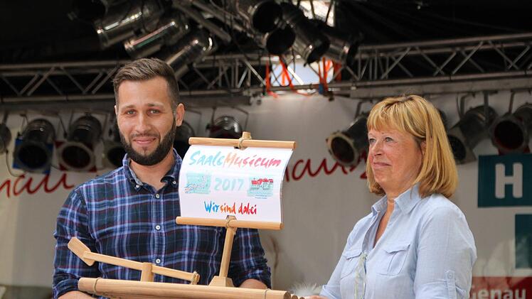 Erdinc Yurdakul übergibt ein Floß an Karin Bauer (Tourist-Info), denn das Stadtfest ist heuer Teil des Kulturfestivals "Saale Musicum". Foto: Ulrike Müller