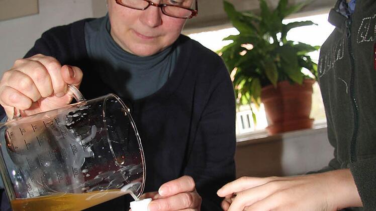 Evi Näher und der neun Jahre alte Jonathan Götz füllen den noch warmen Lippenbalsam in kleine Creme-Tiegelchen.  Fotos: Sonja Adam