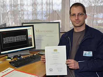 Jungmeister Thorsten Föhrweiser am Konstruktionsplaner und dem Meisterbrief als Metallbauermeister. Er hält die Urkunde, die er zum Meisterpreis der Bayerischen Staatsregierung für die hervorragend absolvierte Meisterprüfung erhielt. Foto: Karl-Heinz Hofmann