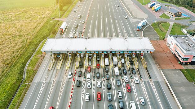 An overhead view of a busy toll road with many cars queuing up to pay the highway toll Blick von oben auf eine stark befahrene Mautstra&szlig;e mit vielen Autos, die Schlange stehen, um die Autobahngeb&uuml;hr zu bezahlen Maut, Mautstation