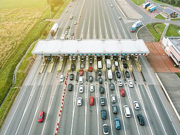 An overhead view of a busy toll road with many cars queuing up to pay the highway toll Blick von oben auf eine stark befahrene Mautstra&szlig;e mit vielen Autos, die Schlange stehen, um die Autobahngeb&uuml;hr zu bezahlen Maut, Mautstation