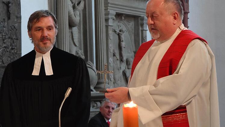 Pfarrer Bernd Grosser (links) und Pater Rudolf Theiler teilen sich das Kreuz, das sie am Palmsonntag im Rahmen des Konzertes der Chöre beider Gemeinden überreicht bekommen haben. Zusammen mit der Osterkerze wandert das Nagelkreuz Jahr für Jahr von Gemeinde zu Gemeinde. Foto: Eckert