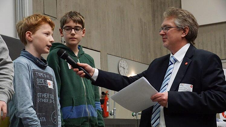 Christian Wershofen (li) erl&auml;utert Michael A. M&uuml;ller, Patenbeauftragter von "Jugend forscht" und Moderator der Preisverleihung, wie er und Maximilian Hildel (re) den "Tic Tac T&uuml;rken" gebaut haben.Pascale Ferry