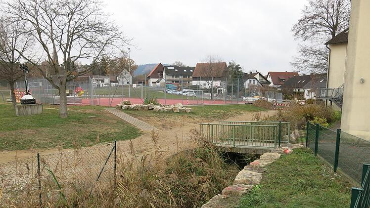 Das Gelände beim Sportplatz der Schule, wo die mobile Baustraße  verlegt werden soll.  Im Vordergrund die Brücke über den Mühlbach, die auf das Tor zwischen  Schule und Sporthalle zuführt. Foto: Dagmar Niemann