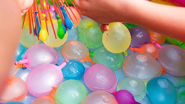 Wasserballon-Spiele f&uuml;r Kinder. Close up von M&auml;dchen f&uuml;llen Wasserballons am sonnigen Tag. Sommer Spa&szlig; im Freien Aktivit&auml;ten f&uuml;r Kinder Konzept