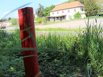 Bisher markieren vier rote Stäbe die Stelle, an die das zukünftige Trafohäuschen hinkommen soll: Und zwar gegenüber der Bahnhofshalle am Hang. Foto: Julia Raab