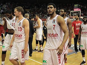 Enttäuscht gehen (v. l.) Trevor Mbakwe, Janis Strelnieks, Daniel Theis, Ryan Thompson, Darius Miller, der nicht zum Einsatz gekommene Josh Duncan und Dawan Robinson vom Feld. Links hinten feiern die Münchner den Sieg. Foto: sportpress