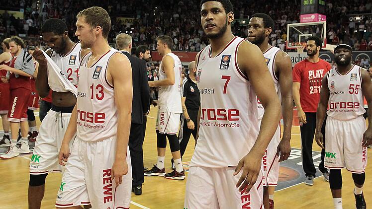 Enttäuscht gehen (v. l.) Trevor Mbakwe, Janis Strelnieks, Daniel Theis, Ryan Thompson, Darius Miller, der nicht zum Einsatz gekommene Josh Duncan und Dawan Robinson vom Feld. Links hinten feiern die Münchner den Sieg. Foto: sportpress