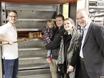 Frisch aus dem Ofen kommen die ersten Markus-Brote. Dabei schauen dem Juniorchef Matthias Wirth (links) Projektleiter Franz Renker, rechts), daneben Viola von Gehlen als Mitarbeiterin und Unterstützerin sowie Tobias Renker mit Elina auf dem Arm zu. Foto: Reinhard Löwisch