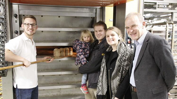 Frisch aus dem Ofen kommen die ersten Markus-Brote. Dabei schauen dem Juniorchef Matthias Wirth (links) Projektleiter Franz Renker, rechts), daneben Viola von Gehlen als Mitarbeiterin und Unterstützerin sowie Tobias Renker mit Elina auf dem Arm zu. Foto: Reinhard Löwisch