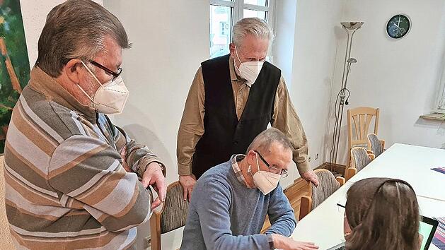 Gerhard Piecyk (sitzend) erklärt der Seniorin eine Funktion an ihrem Laptop; links Helmut Erhardt, hinten Ulrich Ummelmann.