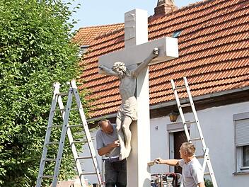 Thomas (rechts) und Michael Brecht von der Firma Brecht aus Zeil bei den letzten Arbeiten an dem Wegkreuz, das im Jahr 1771 in der Dorfmitte von Kirchlauter errichtet wurde. Foto: Günther Geiling
