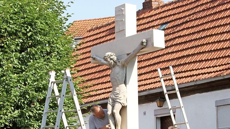Thomas (rechts) und Michael Brecht von der Firma Brecht aus Zeil bei den letzten Arbeiten an dem Wegkreuz, das im Jahr 1771 in der Dorfmitte von Kirchlauter errichtet wurde. Foto: Günther Geiling