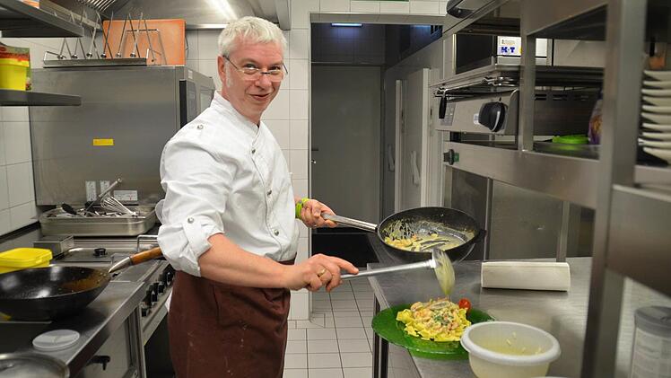 Küchenchef Klaus Brückner bereitet sämtliche Gerichte in seiner Küche frisch zu. Hier füllt er einen Teller mit einer Variation aus Bandnudeln, Flusskrebsen und Spargel. Foto: Kathrin Kupka-Hahn