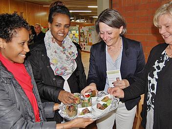 Die Berufsschülerinnen Semrt Chaklu (von links) und Helen Melkomu bieten Berufsschulleiterin Katin Maywald und Fachbetreuerin Doris Peter selbstgemachte Leckereien an. Foto: Sigismund von Dobschütz