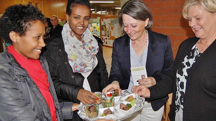 Die Berufsschülerinnen Semrt Chaklu (von links) und Helen Melkomu bieten Berufsschulleiterin Katin Maywald und Fachbetreuerin Doris Peter selbstgemachte Leckereien an. Foto: Sigismund von Dobschütz