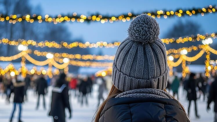 Eine Frau mit Bommelm&uuml;tze verfolgt das Treiben auf einer Eisbahn im Winter