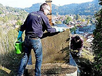 Eine mühevolle Arbeit gerne erledigt. Jürgen Feil (links) und Wilfried Deuerling von der Ortsgruppe des Frankenwaldvereins Steinwiesen reinigen den Sockel des Rollenbergkreuzes. Foto: Siegfried Petrikowski