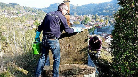 Eine mühevolle Arbeit gerne erledigt. Jürgen Feil (links) und Wilfried Deuerling von der Ortsgruppe des Frankenwaldvereins Steinwiesen reinigen den Sockel des Rollenbergkreuzes. Foto: Siegfried Petrikowski