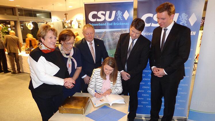 Ins Goldene Buch der Stadt trug sich Staatsministerin Judith Gerlach (sitzend) bei ihrem Besuch in Bad Brückenau ein. Über die Schulter schauten ihr dabei (von links) Bürgermeisterin Brigitte Meyerdierks, Bezirksrätin Karin Renner, Landrat Thomas Bold, der Landtagsabgeordnete Sandro Kirchner und der JU-Kreisvorsitzende Martin Wende. Foto: Rolf Pralle