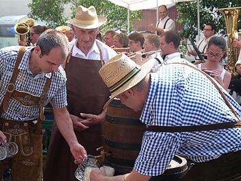 Schaumiger Auftakt: August Winter (hinten), einer der ältesten Einwohner, stach das Festbierfass an. Foto: Gerd Schaar