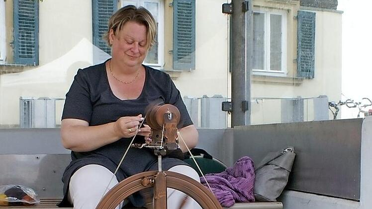 Windgeschützt im Buswartehäuschen präsentiert Kreisheimatpflegerin Annette Schäfer am Spinnrad eine alte Handwerkstechnik. Foto: Renate Neubecker