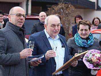 Bürgermeister Gerd Kleinhenz (links) überreicht die Urkunde zur Ernennung als Ehrenbürger des Marktes Wildflecken an Amtsvorgänger Alfred Schrenk (Mitte). Für Ehefrau Rosi gab es einen Blumenstrauß. Foto: Sebastian Schmitt-Mathea