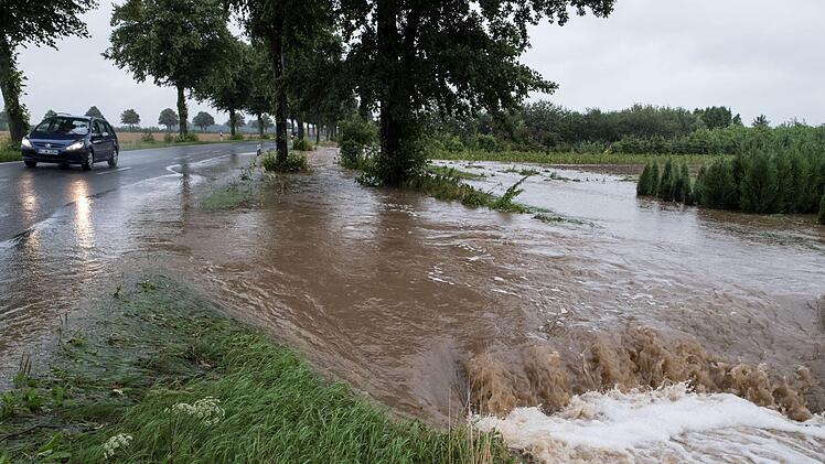 Wasser flie&szlig;t am 25.07.2017 am Rande einer Stra&szlig;e in Springe (Niedersachsen) und &uuml;berflutet Felder. Dauerregen hat in vielen Teilen Deutschlands zu &Uuml;berschwemmungen gef&uuml;hrt. Die Rettungskr&auml;fte sind im Dauereinsatz. Foto: Swen Pf&ouml;rtner/dpa
