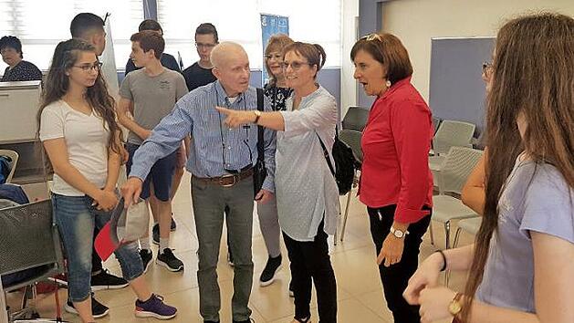 Sch&uuml;ler der Ort-School f&uuml;hren den Ehemann und die Tochter von Hanah Pines, deren Schicksal auf einem Banner dargestellt ist, durch die Ausstellung. Mit im Bild Schulleiterin Liora Hagin (2. v. r.)  Foto: Sivan