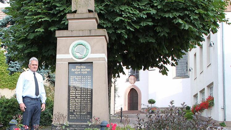 Rosen zum Gedenken an die gefallenen Soldaten: Gilbert Bösl am Denkmal vor der Kirche Oberleichtersbach. Fotos: Sebastian Vogt