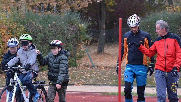 Zahlreiche Übungen standen am Sportplatz des Mehrgenerationenhaus St. Michael am Dienstagvormittag auf dem Programm. Unter anderem musste ein Kind blind auf dem Rad einen Parcour durchfahren. Unterstützung bekam es durch Mitschüler und Lehrkräfte. Foto: Friedrich