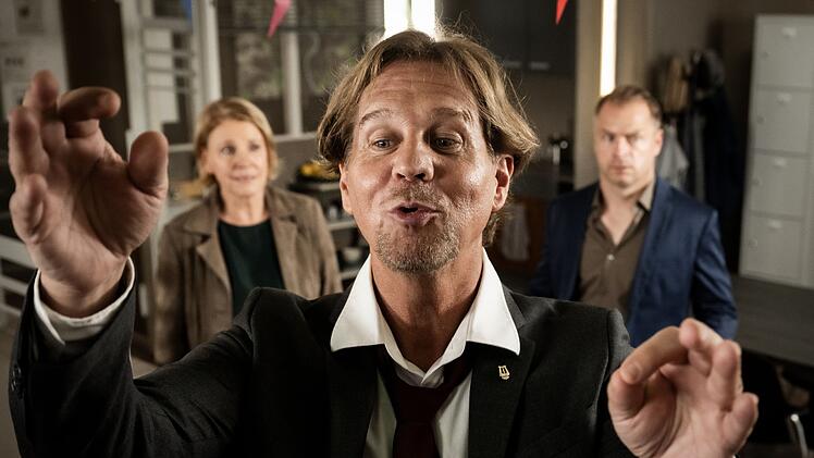 Marie Brand (Mariele Millowitsch) und Jürgen Simmel (Hinnerk Schönemann) sind dabei, als Dr. Engler (Thomas Heinze, vorne) mit gespitzten Lippen den eigenen Jubiläumschor dirigiert.