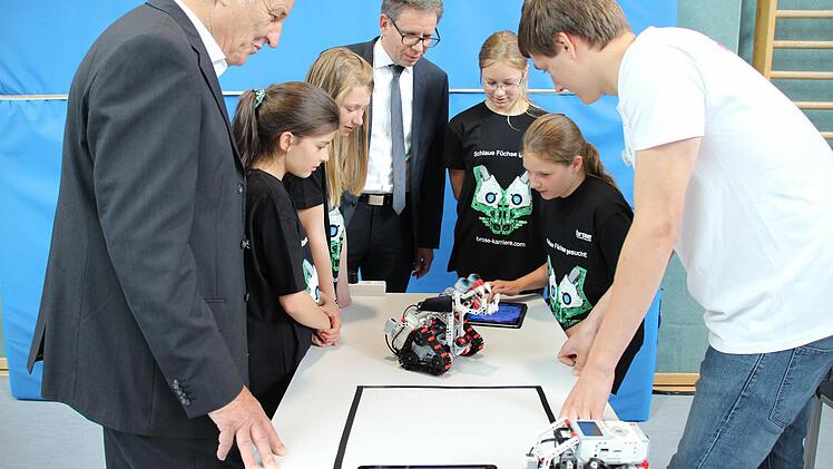 Auch der Pr&auml;sident der Brose Bamberg, Norbert Sieben (links), und Brose-Ausbildungsleiter Michael Stammberger sind wie Sophia, Mia, Steffi und Leni (von links) von dem kleinen Roboter fasziniert. Foto: Fenna Kreuz